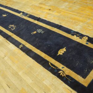 Traditional navy blue hallway runner with a gold border on light wood floors.