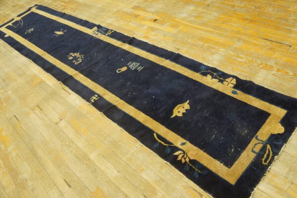 Traditional navy blue hallway runner with a gold border on light wood floors.