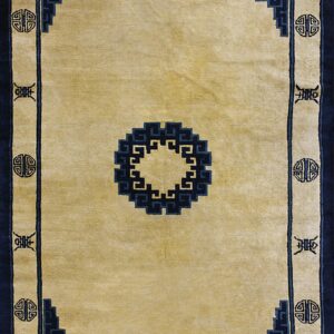 Pale gold rug featuring a navy blue geometric medallion and ornate borders with stylized symbols.
