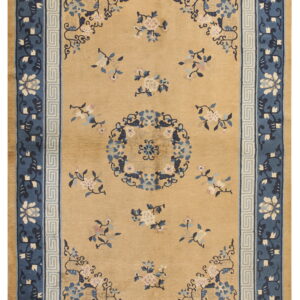 Tan rug with scattered pink and blue floral designs surrounded by a contrasting navy and light blue border.