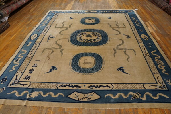 Beige field rug with elaborate dark blue borders and three decorative medallions on hardwood flooring.