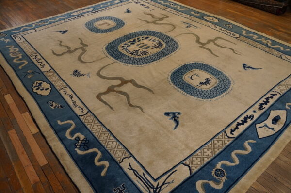 Large beige rug featuring blue scale motifs and abstract symbols within a detailed blue border on wood floors.