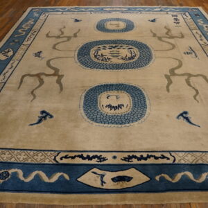 Large tan rug with blue medallions and serpentine figures rests on a warm wood floor.
