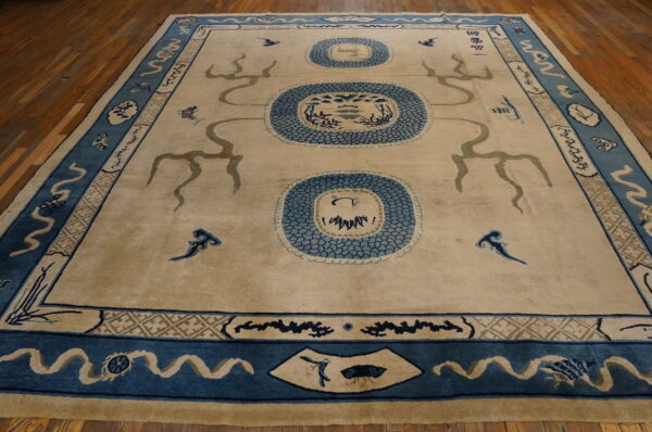 Large tan rug with blue medallions and serpentine figures rests on a warm wood floor.