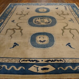 Beige field rug with three central blue scalloped medallions and intricate blue borders on wood.