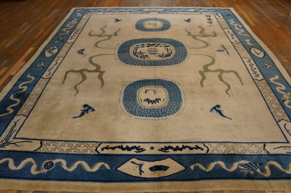 Beige field rug with three central blue scalloped medallions and intricate blue borders on wood.