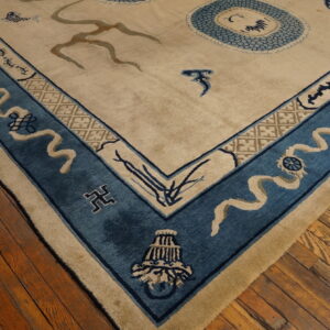 Plush beige rug corner features a wide blue border with symbolic tan ribbon motifs on distressed wood floors.