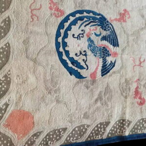 Cream rug detail featuring a bold blue bird medallion, coral accents, and a dotted grey border design.