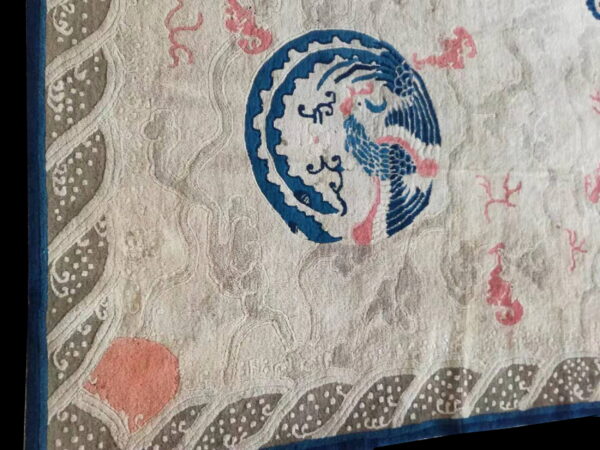 Cream rug detail featuring a bold blue bird medallion, coral accents, and a dotted grey border design.