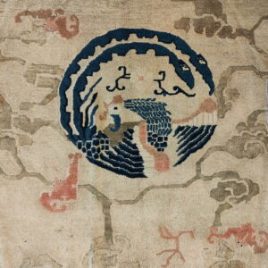 Textured rug detail with a central blue bird motif, surrounded by pale pink and taupe cloud shapes.