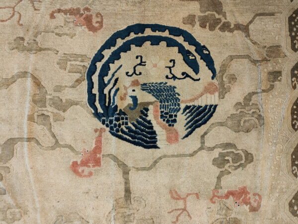 Textured rug detail with a central blue bird motif, surrounded by pale pink and taupe cloud shapes.