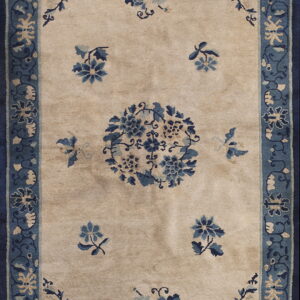 A beige rug with a blue floral pattern, including a central medallion and complex blue borders.