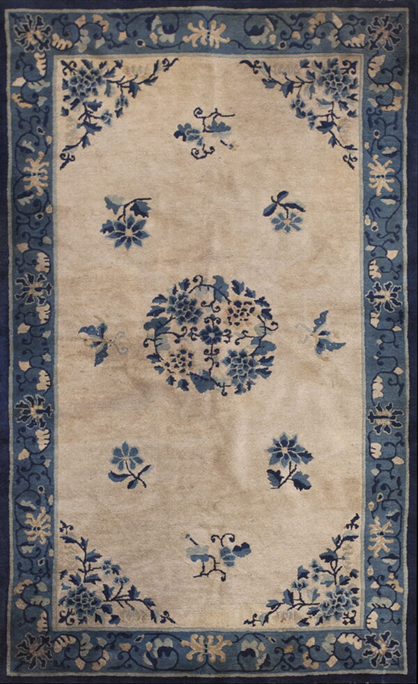 A beige rug with a blue floral pattern, including a central medallion and complex blue borders.