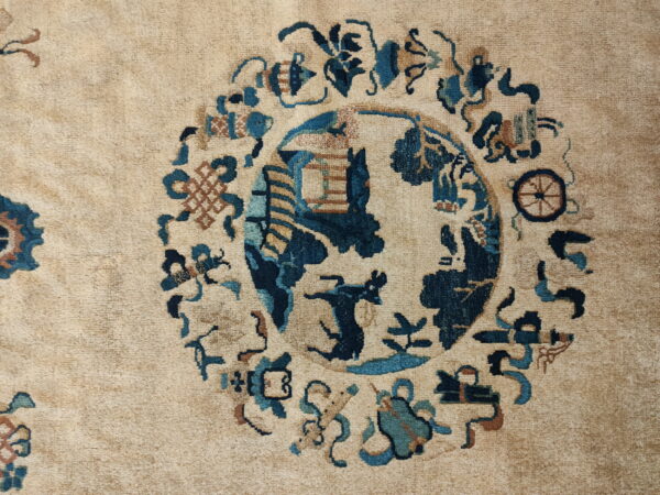 A beige rug showing a round medallion pattern with deep blues, teal, and reddish-brown motifs.