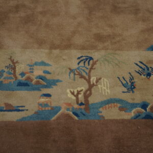 Detailed view of a tan rug with an elaborate scenic pattern bordered by solid medium brown pile.