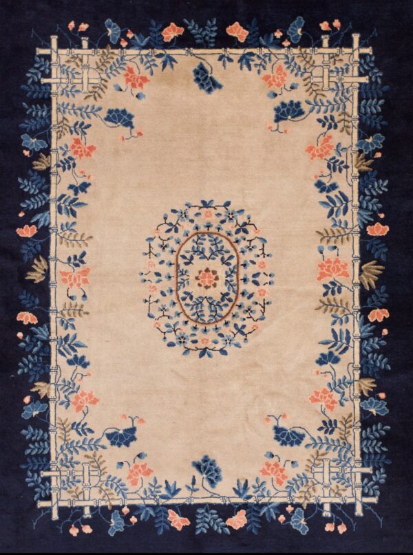 A cream rug featuring a dark blue floral medallion and border is displayed on wide wood planks.