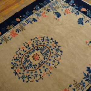 Tan rug with a central floral medallion and a deep navy border over hardwood floors.