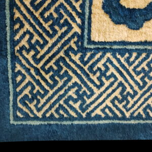 Detail of a high-pile rug featuring blue and beige geometric key pattern border designs.