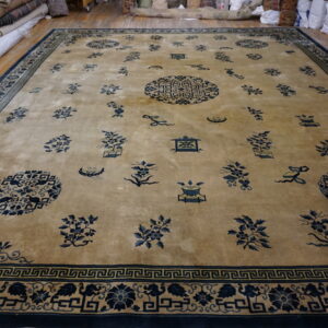 Large tan rug featuring scattered navy blue medallions and floral motifs, framed by a complex border.