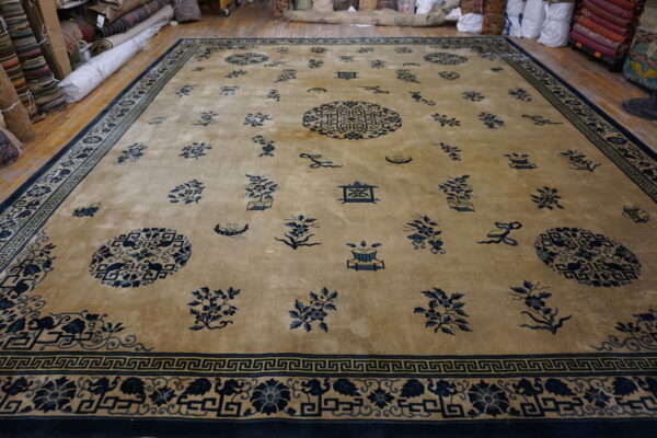 Large tan rug featuring scattered navy blue medallions and floral motifs, framed by a complex border.