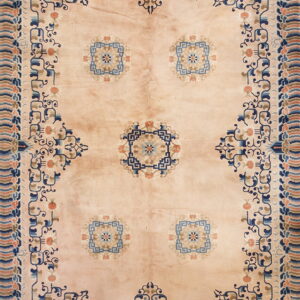 Pale peach rug with stylized dark blue and coral medallions and an elaborate blue and peach border.
