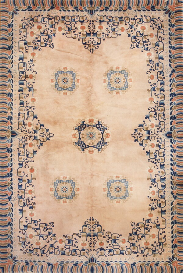 Pale peach rug with stylized dark blue and coral medallions and an elaborate blue and peach border.