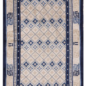 Beige and blue rug featuring a diamond trellis field and wide borders with geometric and Greek key patterns.