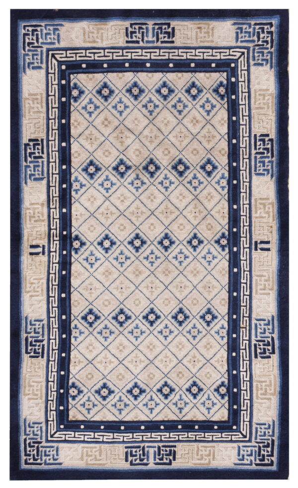 Beige and blue rug featuring a diamond trellis field and wide borders with geometric and greek key patterns.