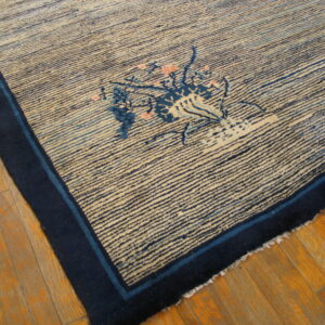 Cream rug with dense horizontal blue stripes, dark blue border, and a pink floral vase motif on hardwood.