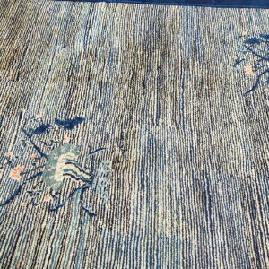 Textured rug featuring vertical indigo and beige stripes with scattered stylized blue and coral floral accents.