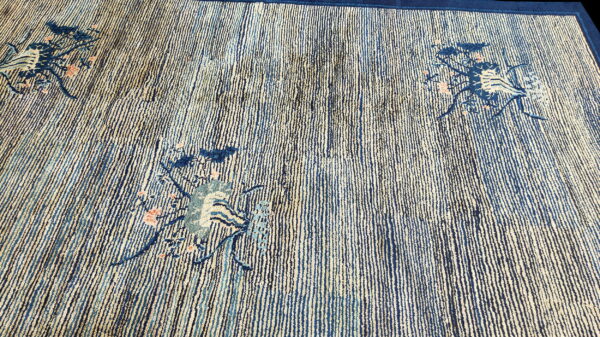 Textured rug featuring vertical indigo and beige stripes with scattered stylized blue and coral floral accents.