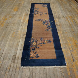 Brown runner with a dark blue border and blue and gold floral sprigs on distressed wood planks.