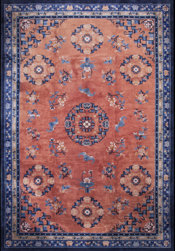 Coral-red rug with ornate blue and ivory floral medallions, stylized bats, and a deep blue geometric border.