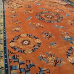 Plush, rust-colored rug displaying scattered blue and yellow medallions and detailed multicolored borders on a wood floor.
