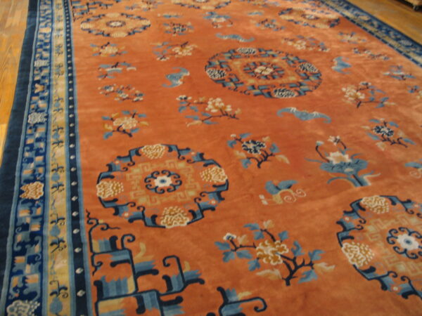 Plush, rust-colored rug displaying scattered blue and yellow medallions and detailed multicolored borders on a wood floor.