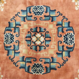 Plush orange rug featuring a navy and teal geometric medallion surrounded by pale floral motifs.