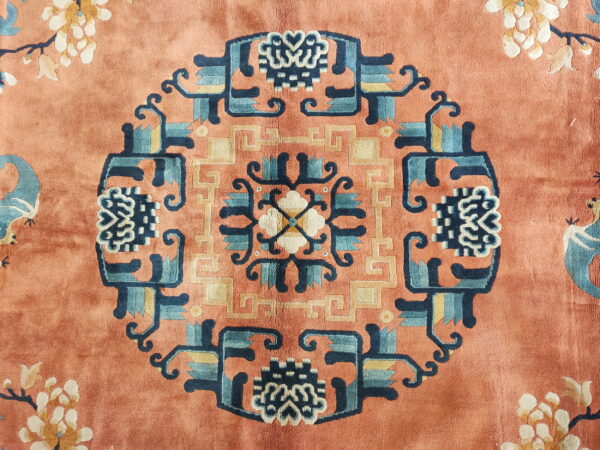 Plush orange rug featuring a navy and teal geometric medallion surrounded by pale floral motifs.