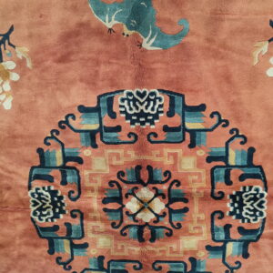 Plush salmon rug detail with a blue-green bat and multi-colored geometric central medallion design.