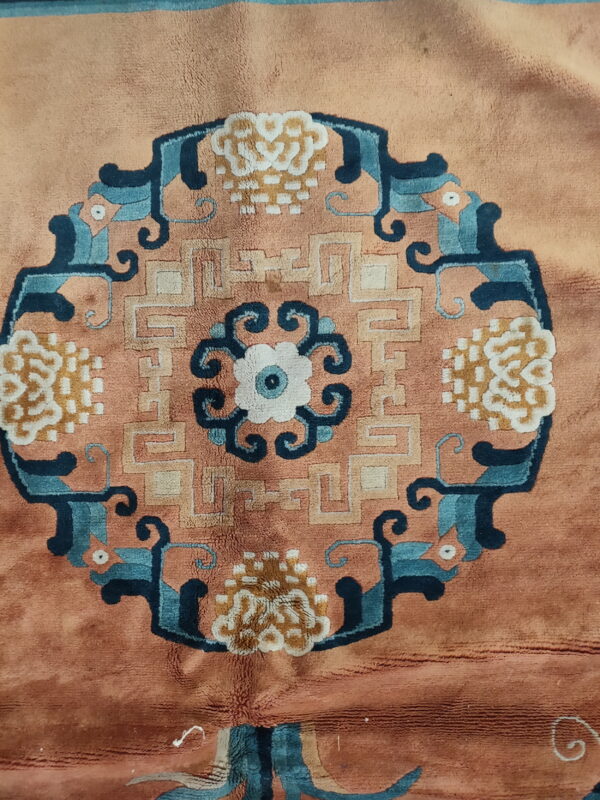 Close-up of a high-pile rug showing a central medallion in blue, cream, tan, and rust.