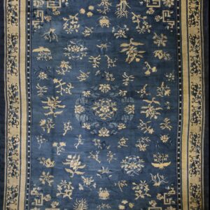 Dark blue rug featuring scattered tan floral and bird motifs and a wide tan decorative border.