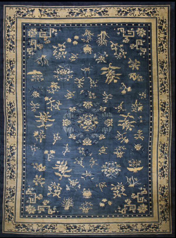 Dark blue rug featuring scattered tan floral and bird motifs and a wide tan decorative border.