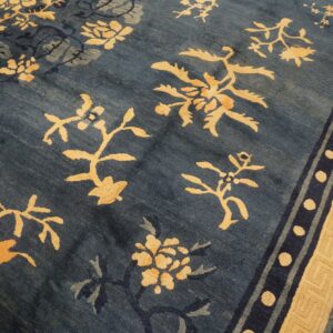 Deep blue rug with scattered gold botanical designs and a wide beige meander border.