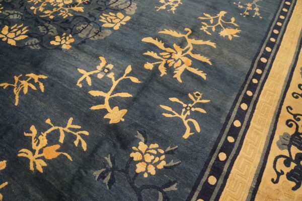 Deep blue rug with scattered gold botanical designs and a wide beige meander border.