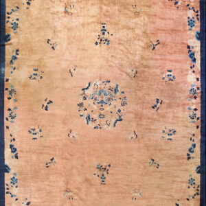 Low-pile rug featuring a dusty rose field with a central design and scattered blue floral motifs within a navy border.