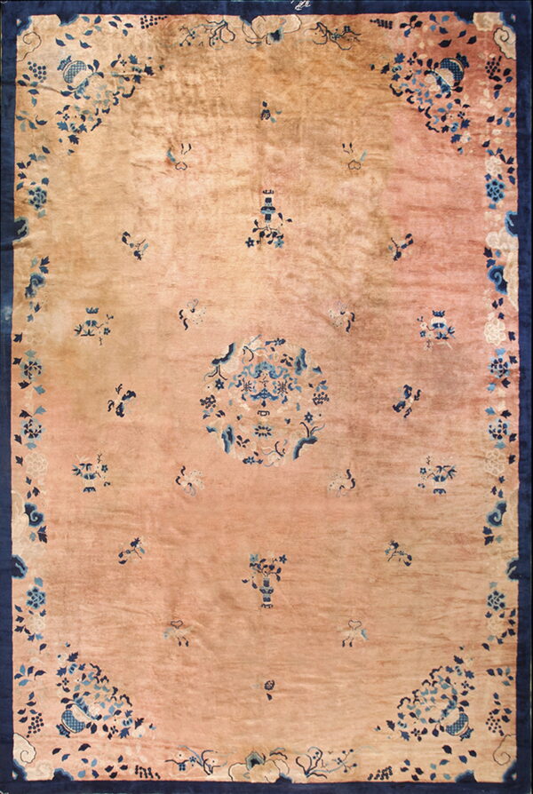 Low-pile rug featuring a dusty rose field with a central design and scattered blue floral motifs within a navy border.