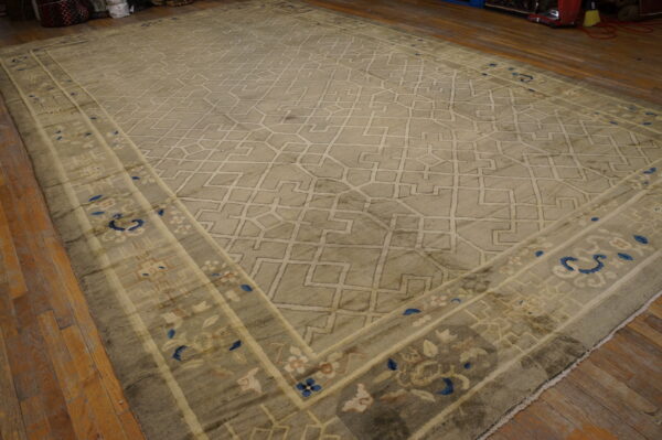 Sage rug with a geometric lattice pattern and floral border detailing in blue and cream on wood flooring.