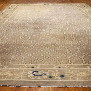 A large taupe rug with a light geometric lattice pattern sits on polished dark hardwood floors.