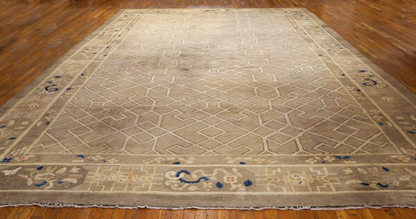 A large taupe rug with a light geometric lattice pattern sits on polished dark hardwood floors.