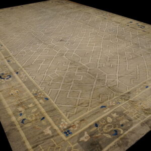 A large gray rug with a light geometric field pattern and a floral border accented with blue.