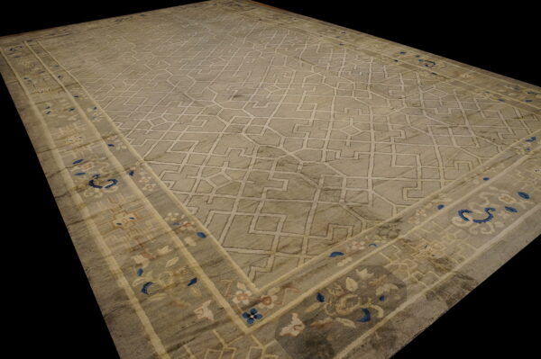 A large gray rug with a light geometric field pattern and a floral border accented with blue.